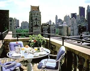 A balcony with a table and chairs overlooking the city for a girlfriend getaway over the holidays in NYC.