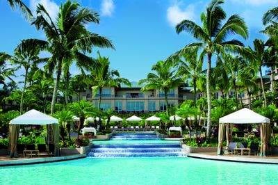 A pool surrounded by palm trees and lounge chairs at the Ritz-Carlton, Maui.