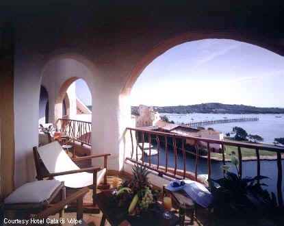 A balcony overlooking a lake with chairs and a view at the Presidential Suite of Hotel Cala di Volpe.