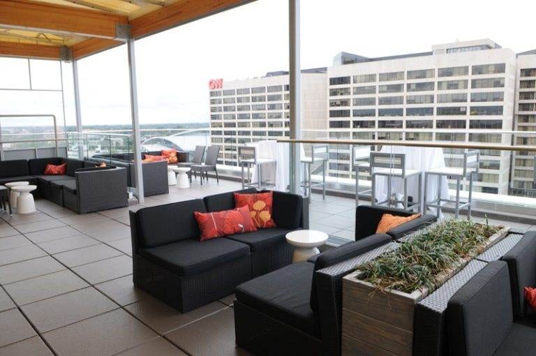 A rooftop patio at the Glenn Hotel in Atlanta with black furniture and a view of the city.