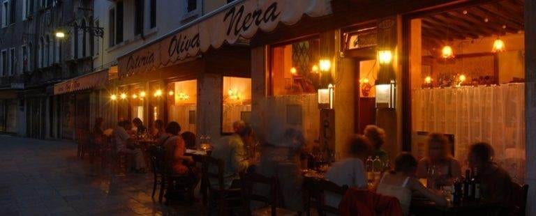A group of people sitting at Olive Nera restaurant in Venice, Italy at night.