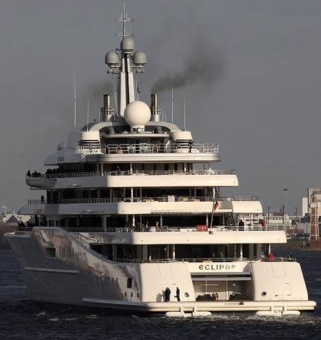 A large white superyacht with smoke coming out of it.