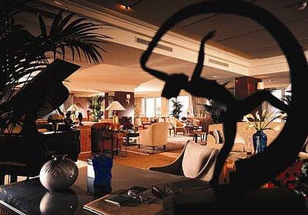 A living room with a piano and a statue in Switzerland, The Royal Penthouse Suite :: Geneva.