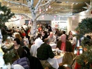 A crowd of people gathered at tables in a restaurant, enjoying a girlfriend getaway in NYC.
