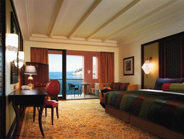 A hotel room with a balcony overlooking the ocean at Al Jissah.