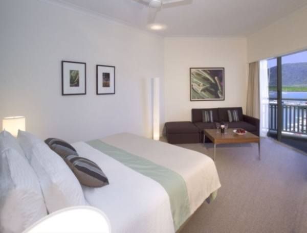 A room with a bed and a balcony overlooking the water at Shangri La Hotel The Marina in Cairns.