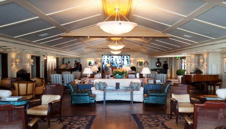 A large living room with couches, chairs, and a piano in Shutters on the Beach hotel in Santa Monica, CA.