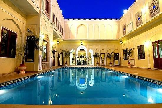 A swimming pool at night in a luxury hotel courtyard.