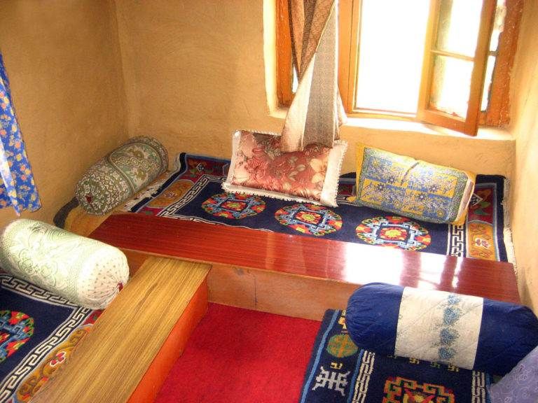 A room with a bed, pillows, and a window in Kaza, Spiti Valley.