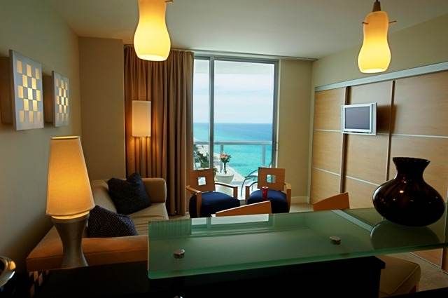 A living room with a European Riviera style and a view of the ocean on the sandy beach of Sunny Isles.