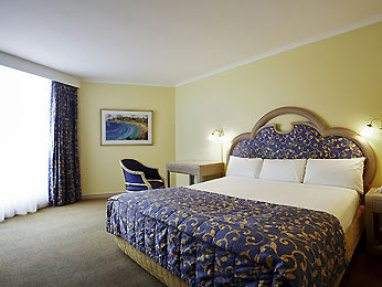 A beachfront hotel room with a bed and a desk.