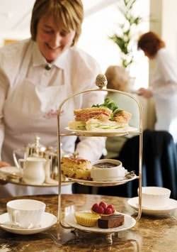 A young woman serving tea at a table in a restaurant in Harrogate, England.