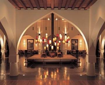 The lobby of a hotel with arches and chandeliers, redefining the life of Sultanate at The Chedi Muscat.