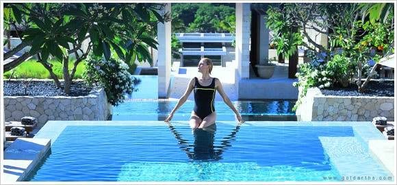 A woman standing in a pool wearing a black swimsuit.