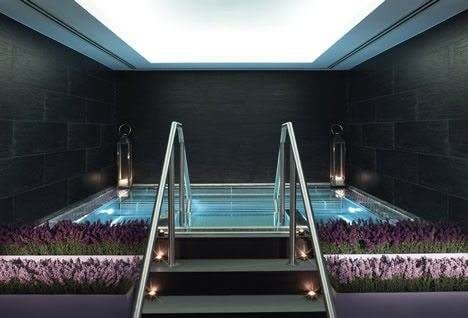 An indoor pool at the historic Langham London with steps leading up to it.
