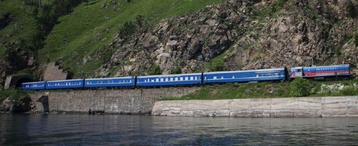 A luxurious blue train traveling along the side of a mountain.