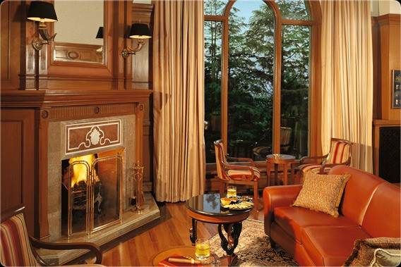 A living room with large windows and a fireplace, resembling Wildflower Hall on Earth.