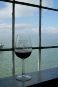 A glass of wine sits in front of a window overlooking the ocean at the Zap Festival.