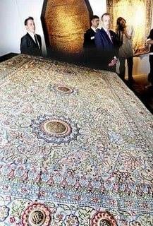 A large rug is on display in a museum, showcasing a magnificent piece of art.