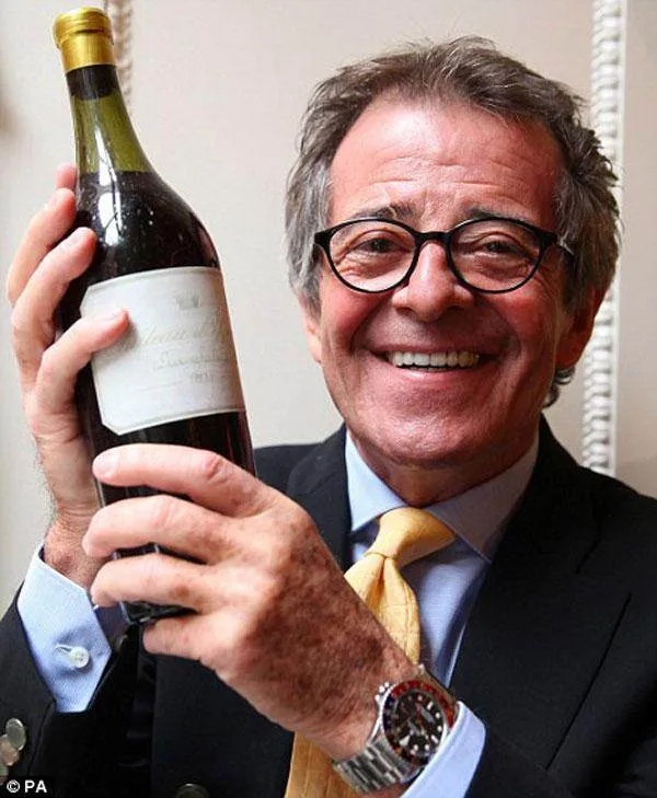 A man holding up a bottle of wine.
