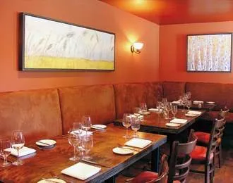 A dining room with orange walls and wooden tables offering gastronomical pleasures.