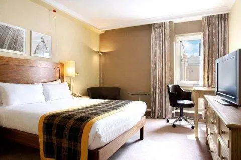 A hotel room at The Islington Hotel in Tasmania, featuring a bed, desk, and television.