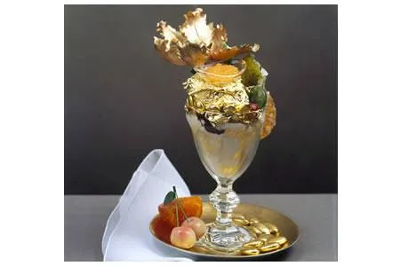 A lip-smacking gold ice cream waiting to melt in a glass on a plate.