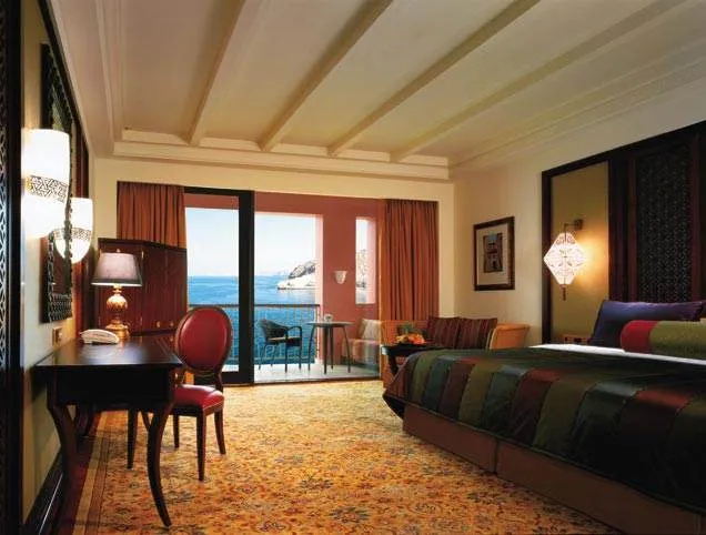 A hotel room with a balcony overlooking the ocean at Al Jissah.