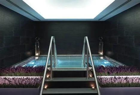 An indoor pool at the historic Langham London with steps leading up to it.