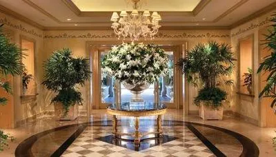 The entrance to a glamorous home in Beverly Hills has a marble floor and a chandelier.