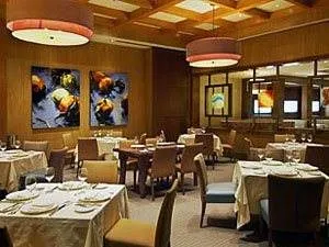 A restaurant with wooden ceilings and tables and chairs.