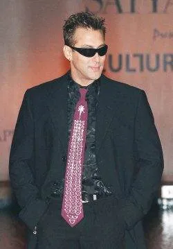 A man in a suit and tie standing on a runway wearing an expensive designer necktie.