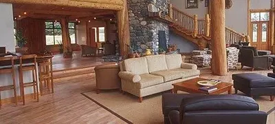 A large living room in a log home nestled in a rustic landscape graced with untouched nature.