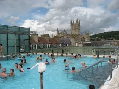 A large group of people enjoying themselves in an outdoor swimming pool in Bath, England.