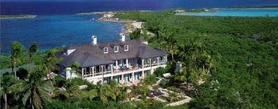 An aerial view of a romantic house on top of a hill overlooking the ocean.