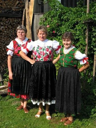 Three women in traditional Polish costumes posing for a photo.