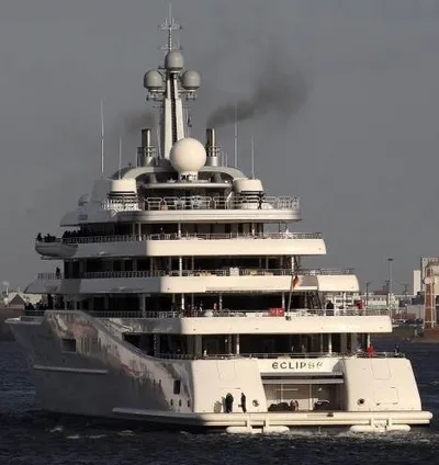 A large white superyacht with smoke coming out of it.