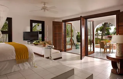 A bedroom with a large bed and a balcony in Cap Juluca, showcasing Moorish architecture surrounded by nature.