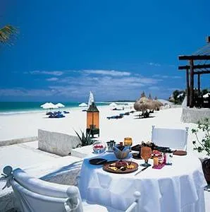 A white table and chairs are set up on the beach at Maroma Resort and Spa.