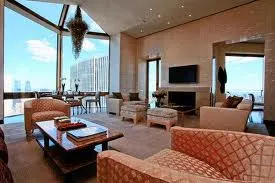A luxury living room with large windows overlooking the city at Ty Warner Penthouse, Four Seasons in New York.