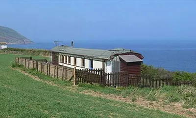 A small caravan on a grassy hill next to the ocean in Wales.