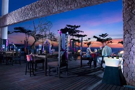 A restaurant with a view of the ocean at dusk in Bali.