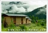 A wooden house in the mountains surrounded by clouds.