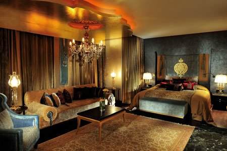 A luxurious bedroom with a large bed and a chandelier located in the Mardan Palace Hotel, Turkey.