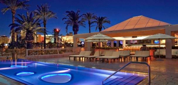 The New Hard Rock Tower Hotel offers a pool with lounge chairs and palm trees at night.
