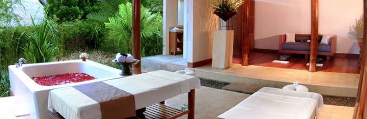 A Balinese spa room with a massage table and chairs.