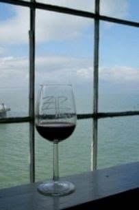 A glass of wine sits in front of a window overlooking the ocean at the Zap Festival.